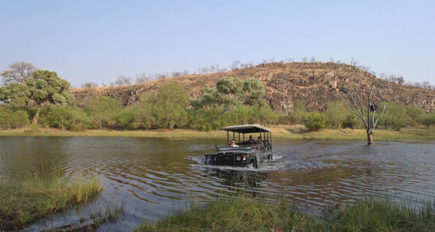 A safari vehicle drives through feet of water to look for wildlife in Botswana