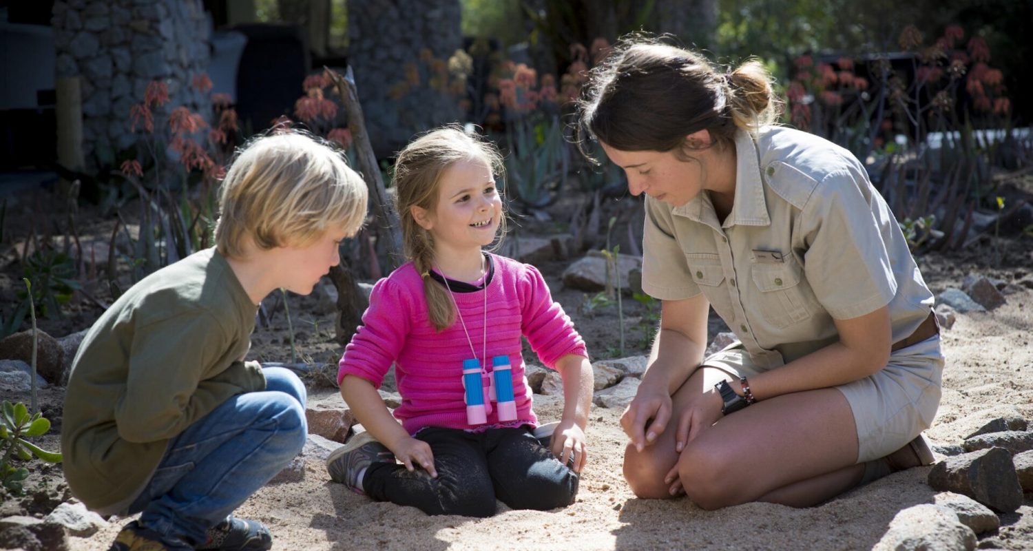 A safari guide teaches two young kids about tracking wildlife at andBeyond Ngala Safari Lodge, South Africa